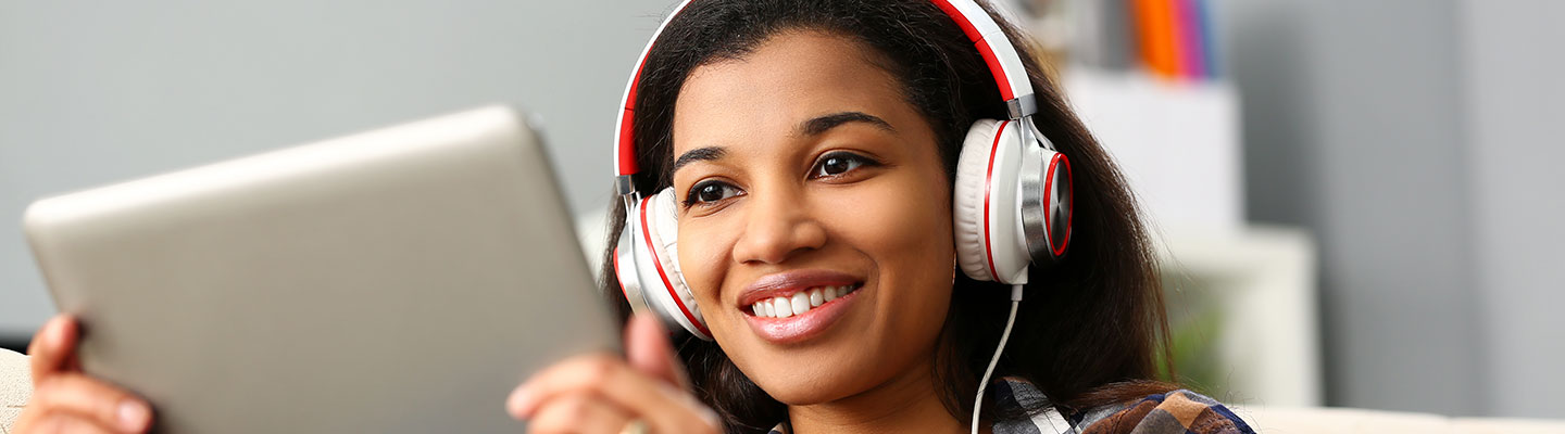 young woman using tablet to browse web with headphones on
