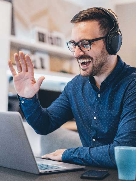man wearing headphones waving at webcam