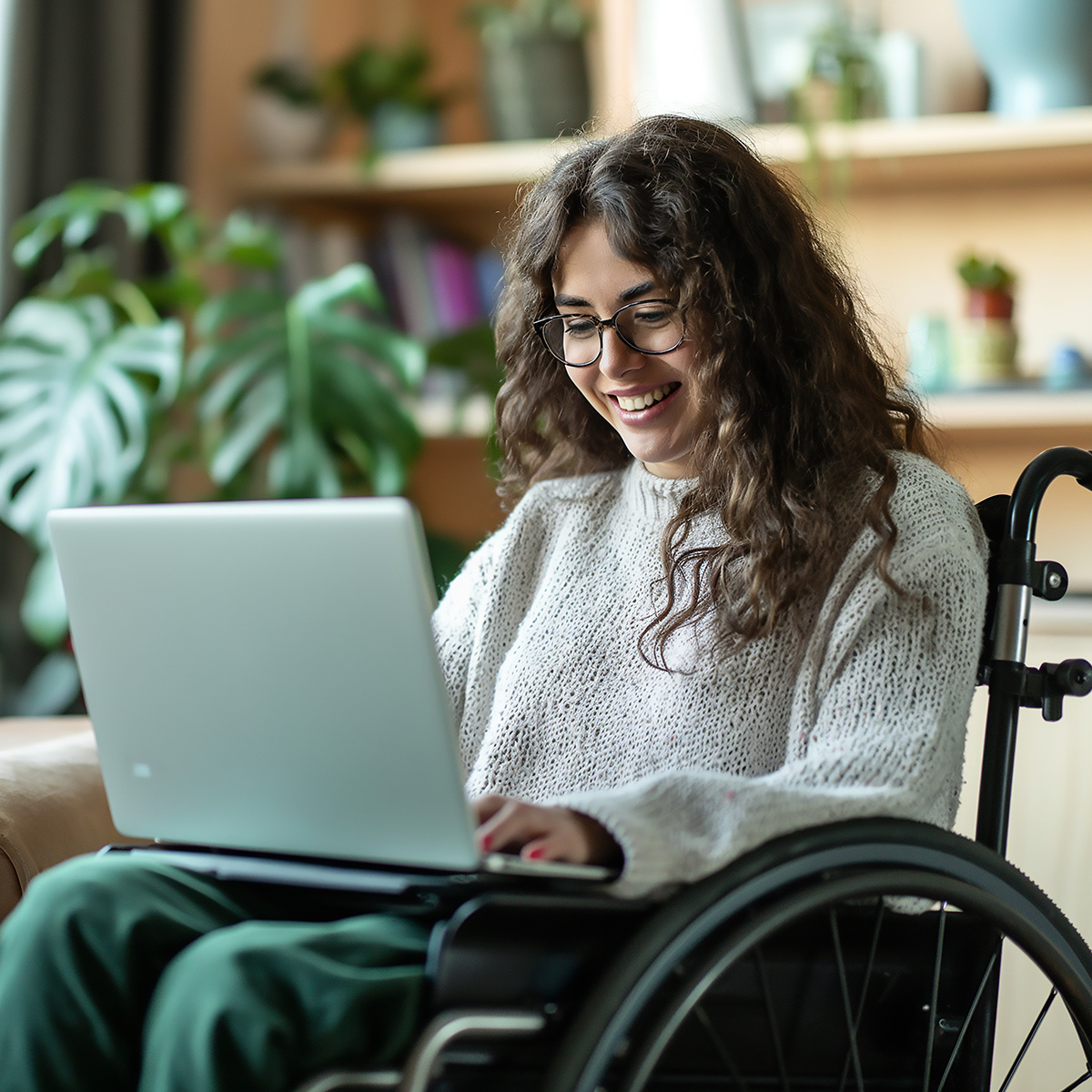 image of young female in wheelchair using laptop computer in office